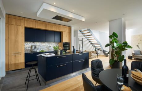 Tipps & Tricks bild 1 Moderne Küche mit dunkelblauen Fronten, Holzverkleidung und Kücheninsel in offenem Wohnbereich – Tipps im Küchen Ratgeber